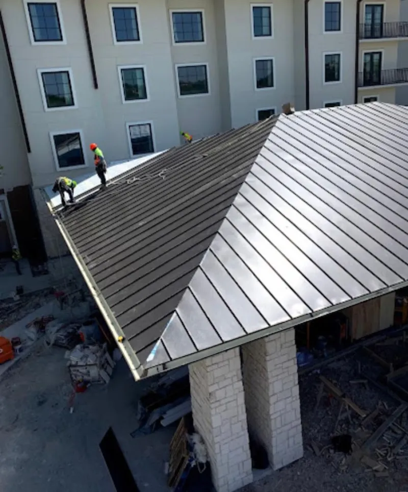 Crew installing standing seam metal roof panels on a commercial project in Perryton